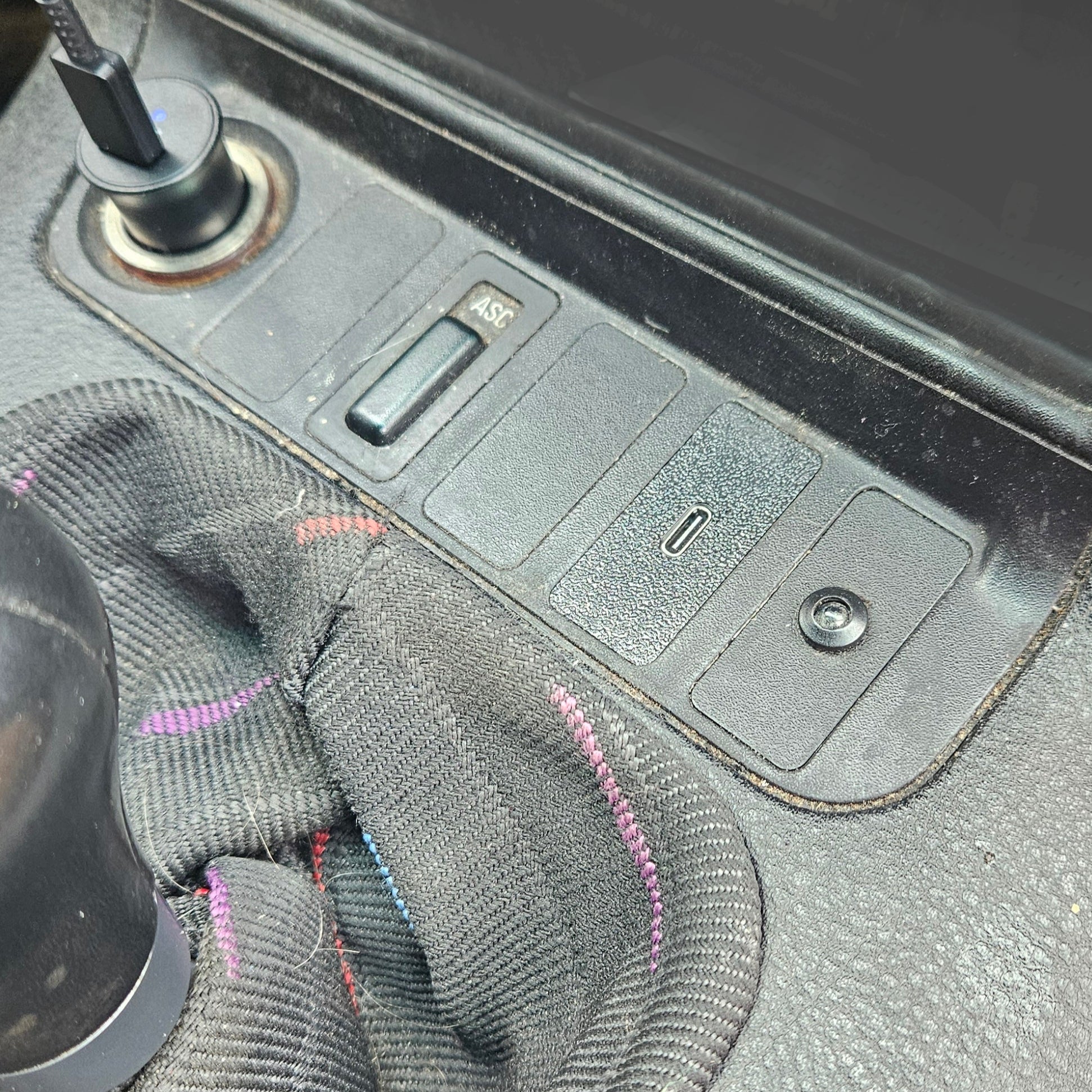 Close-up of a car's dashboard with a radio and gear shift, showing a USB C charger