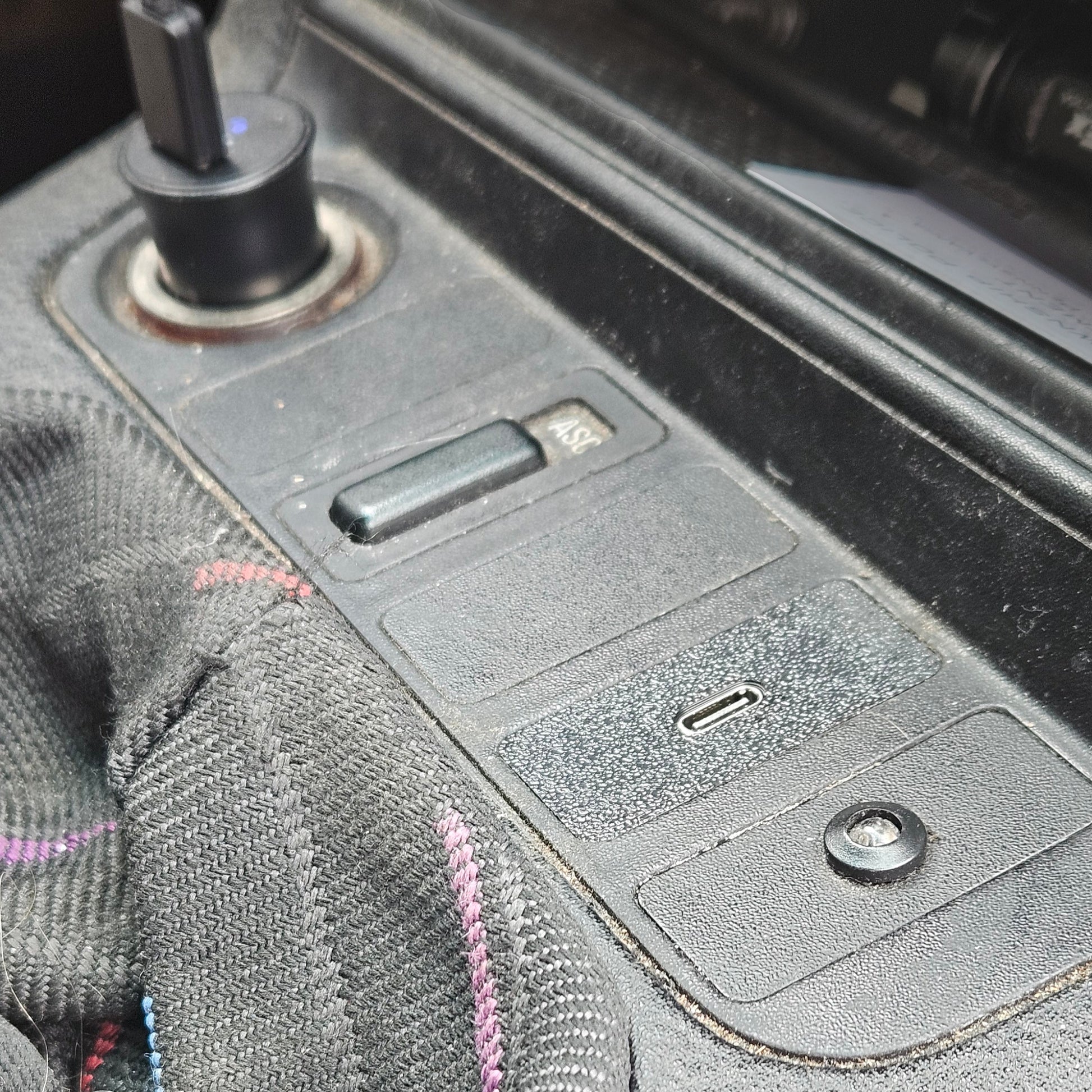 Close-up of a car's USB charging port with a cable plugged in.